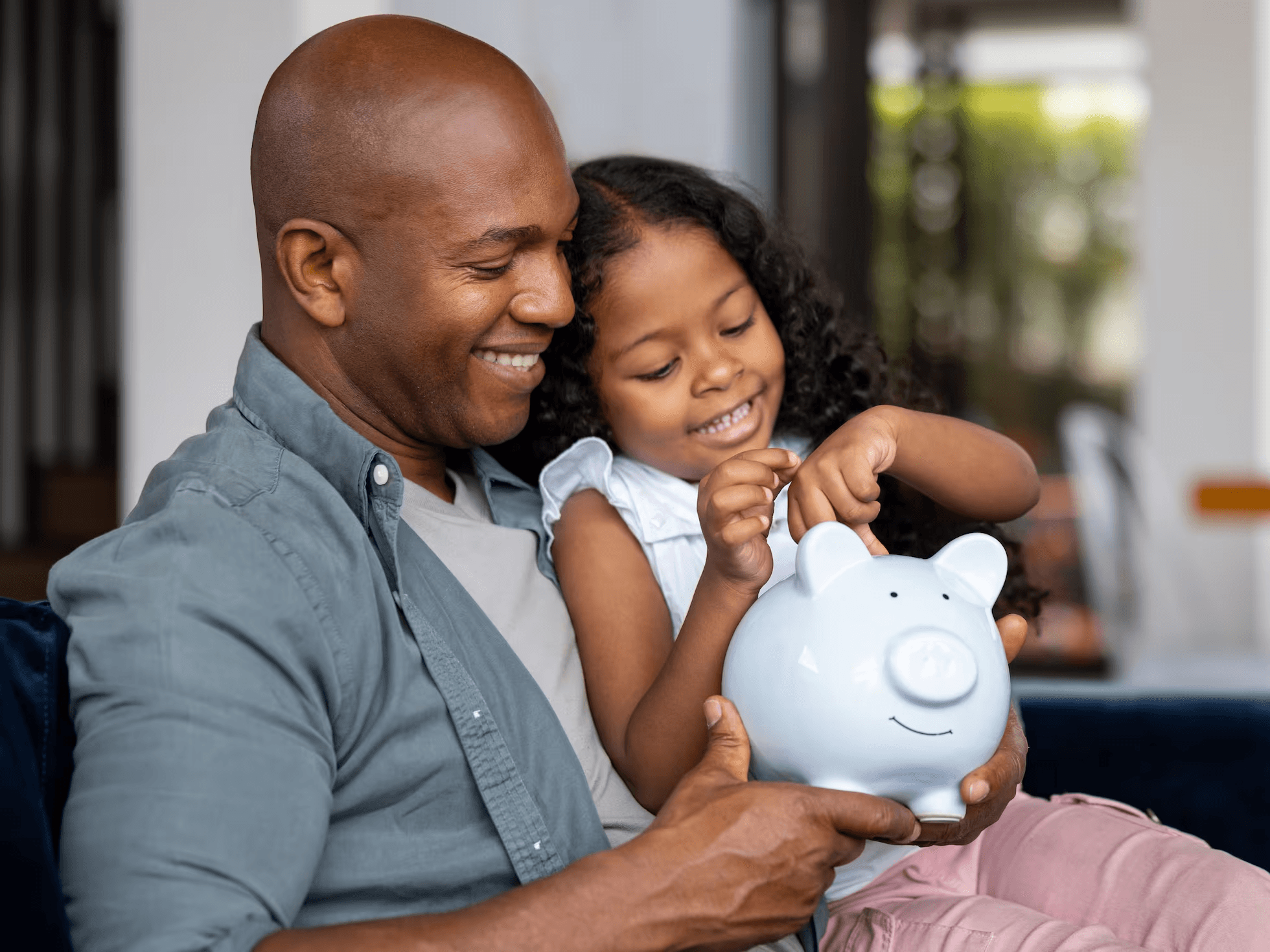 Padre e hija sonriendo mientras guardan una moneda en una alcancía juntos